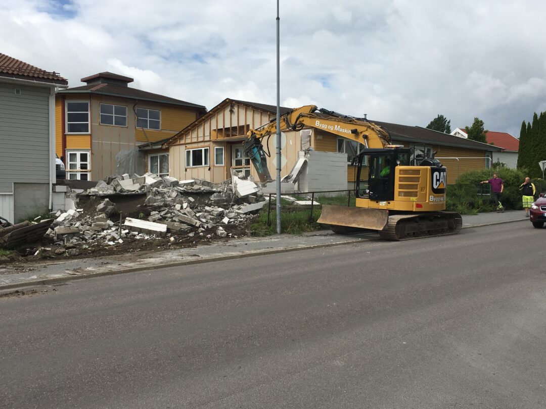 Bilde av levegg som rives med gravemaskin