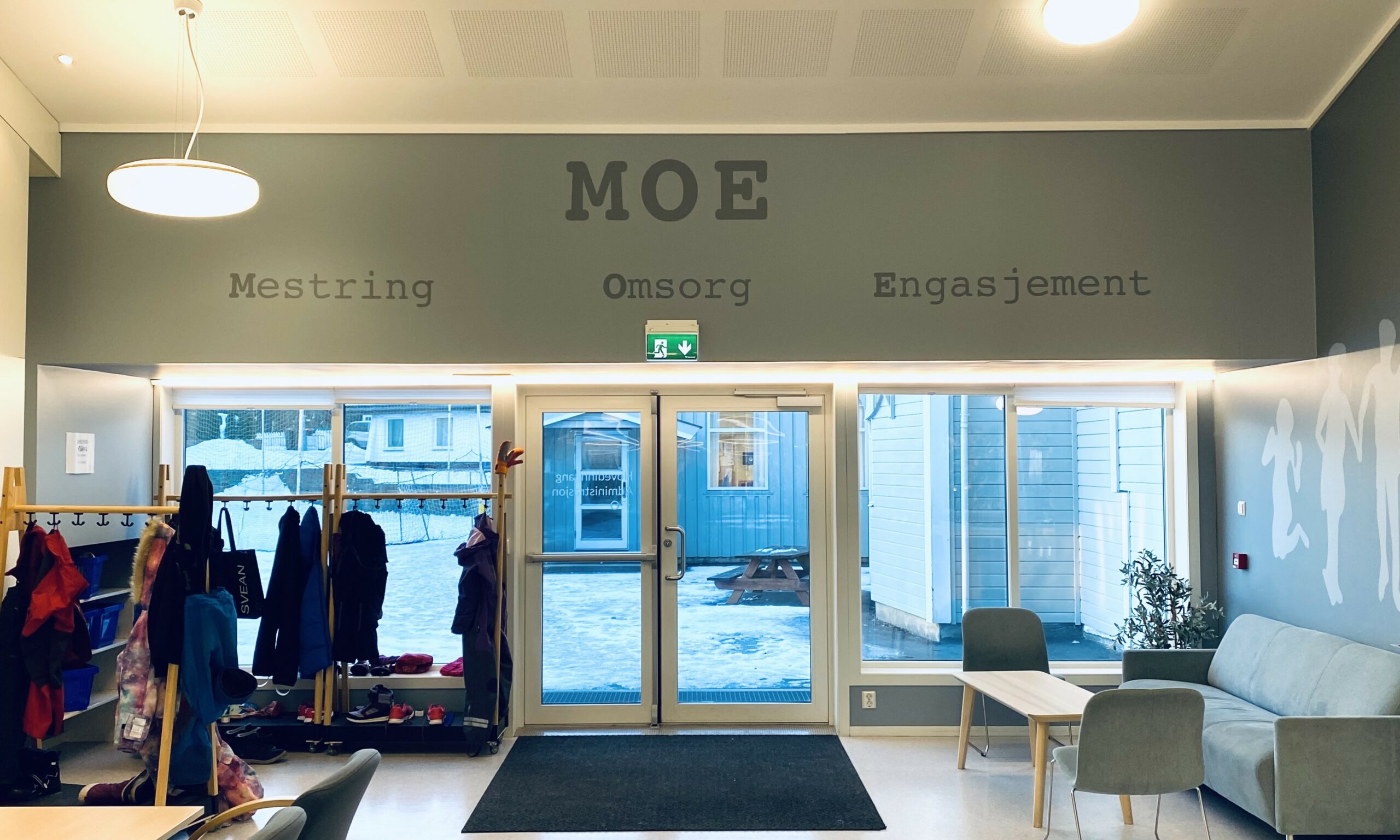Bilde MOE-navnet over utgangsdøra i allrommet - med ordene Mestring - Omsorg - Engasjement.