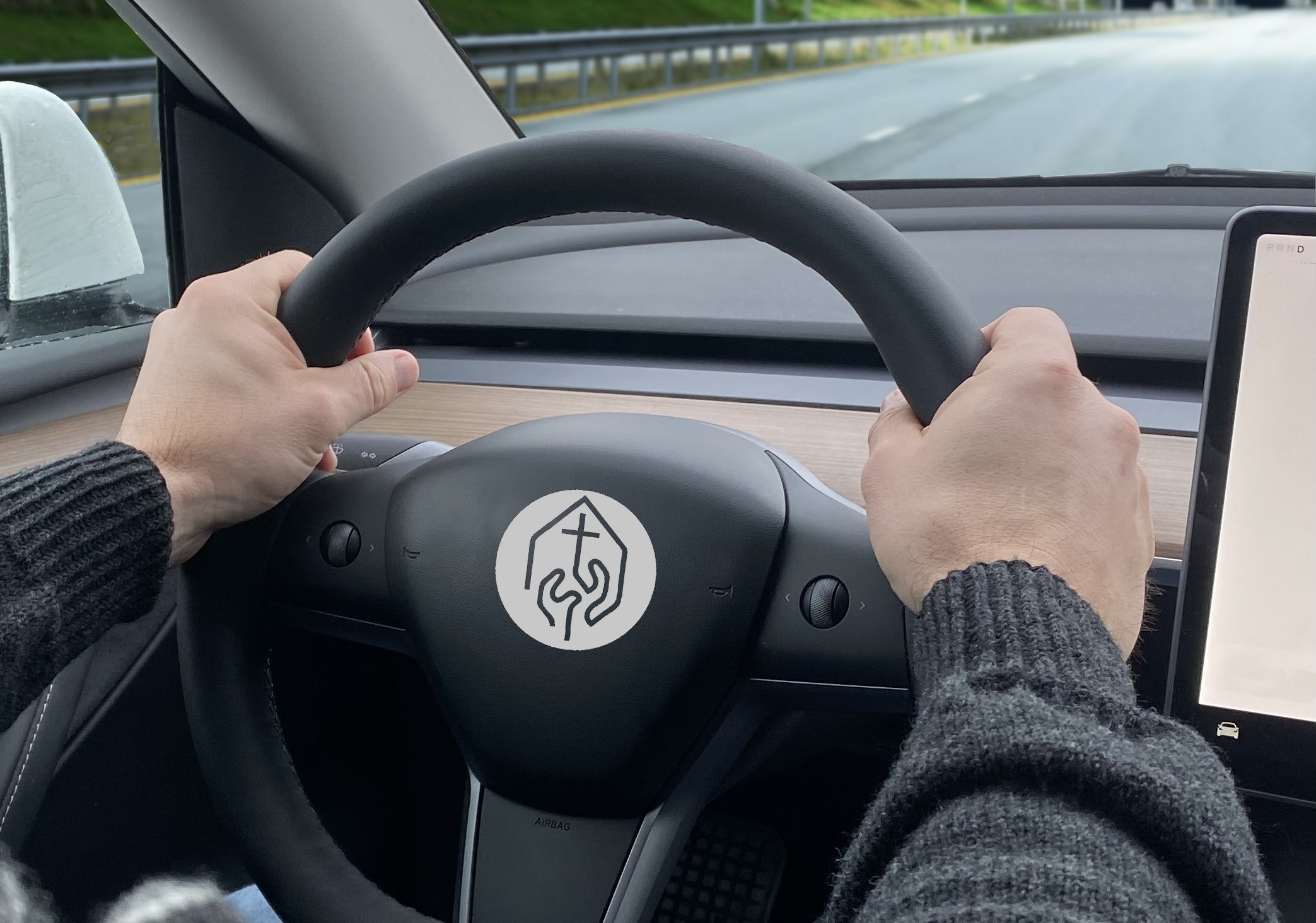 Bilde av to hender som holder i et ratt med DELK-logo i midten.