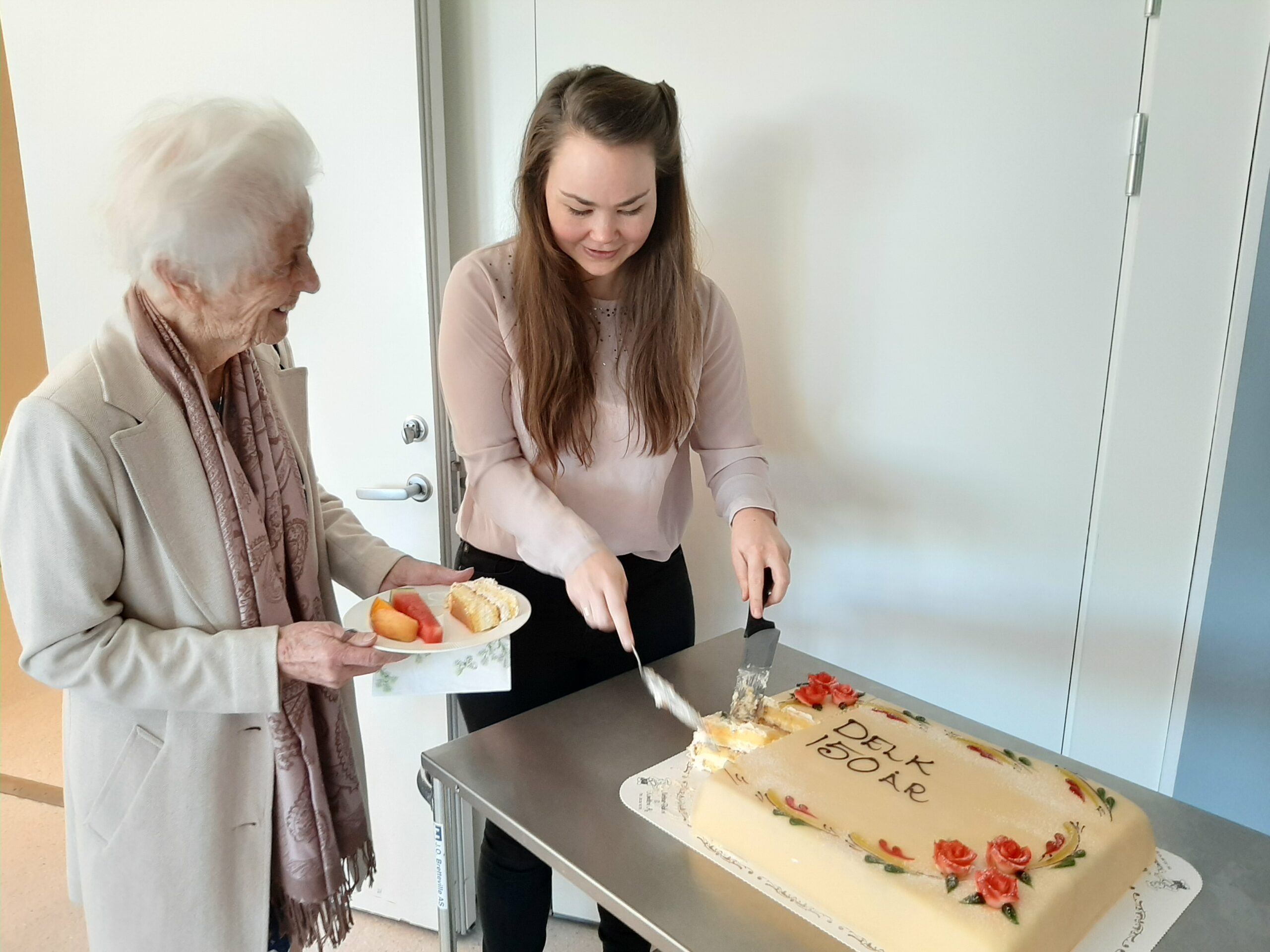 Bilde av Jenny Andrine Johansen som serverer marsipankake til Sigrid Bjanger