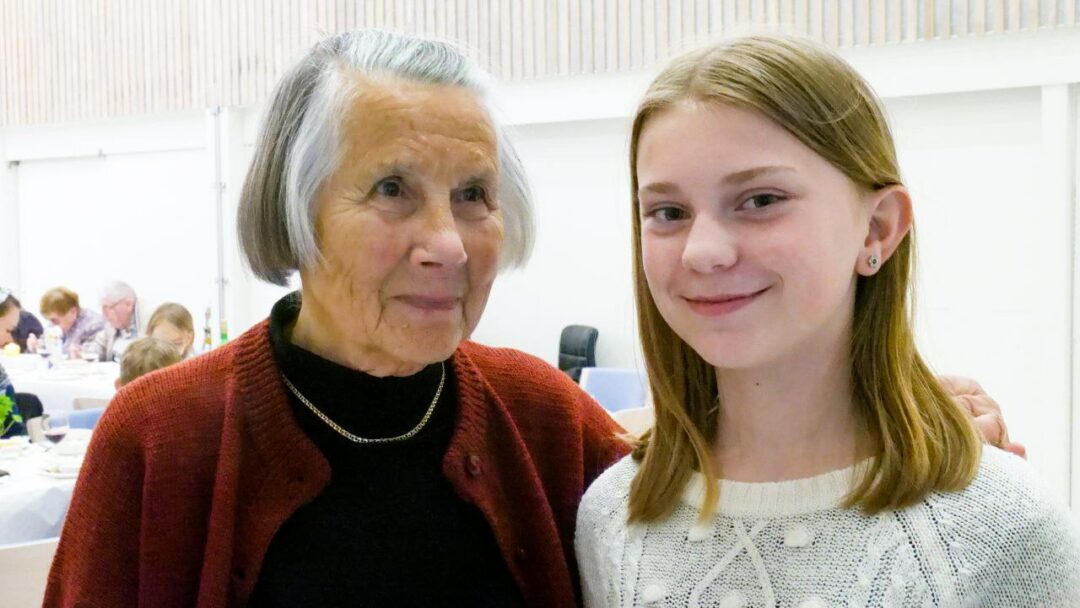 En ung jente og en eldre dame står sammen i kirken.