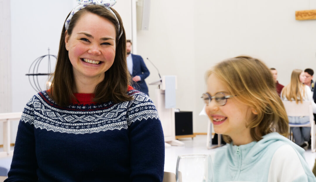 Blid mor og datter sitter til bords i kirkerommet i Moe kirke