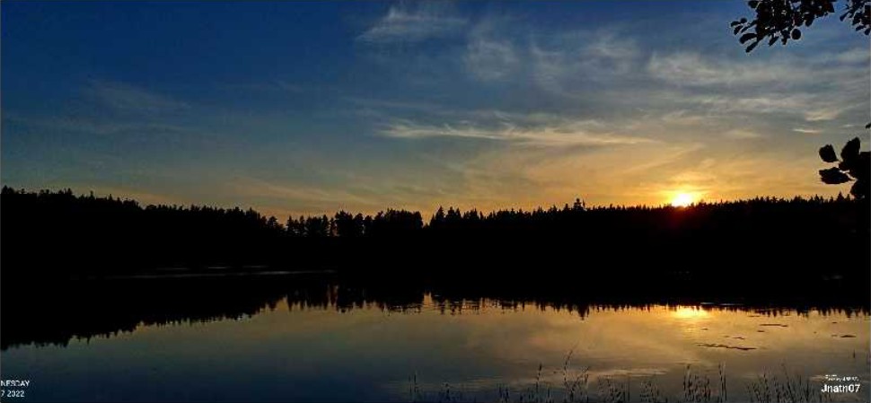 Solnedgang over en rolig innsjø.