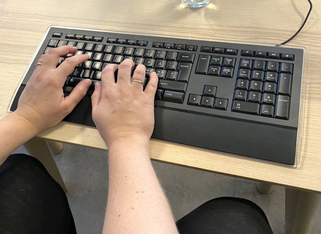 Nærbilde av to hender som skriver på tastatur.