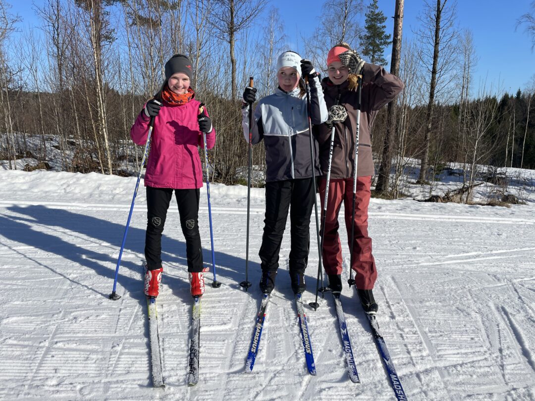 Tre blide jenter myser mot sola på skidag i Storås.