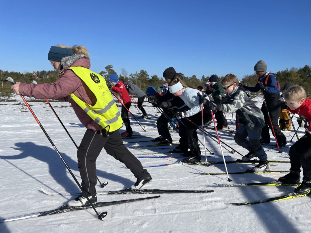 Rektor Beate leder an i en mengde elever i full fart på ski.