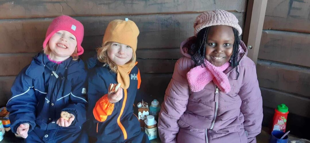 Tre blide jenter koser seg med mat i gapahuken på skidag.