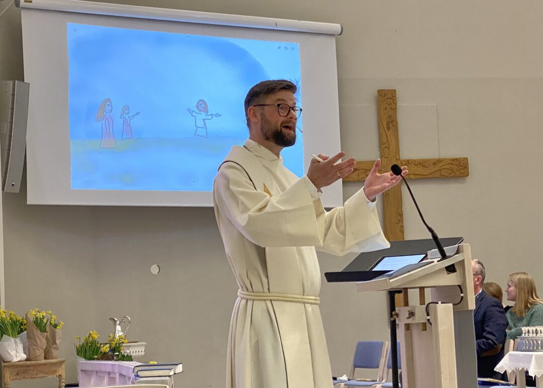 Erling Rantrud som tegner under påskepreken. Lerret med direktetegning i bakgrunnen.