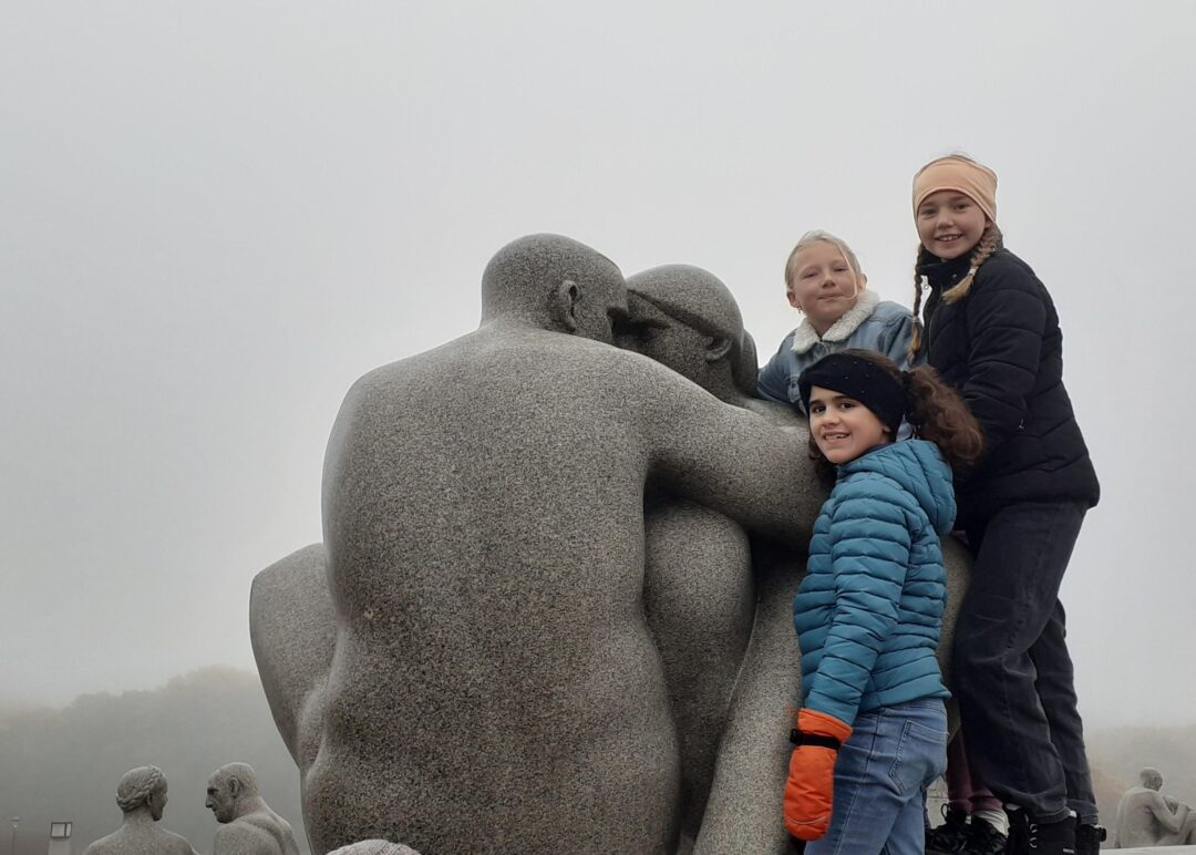 Bilde av tre jenter som klatrer på en statue i Frognerparken.