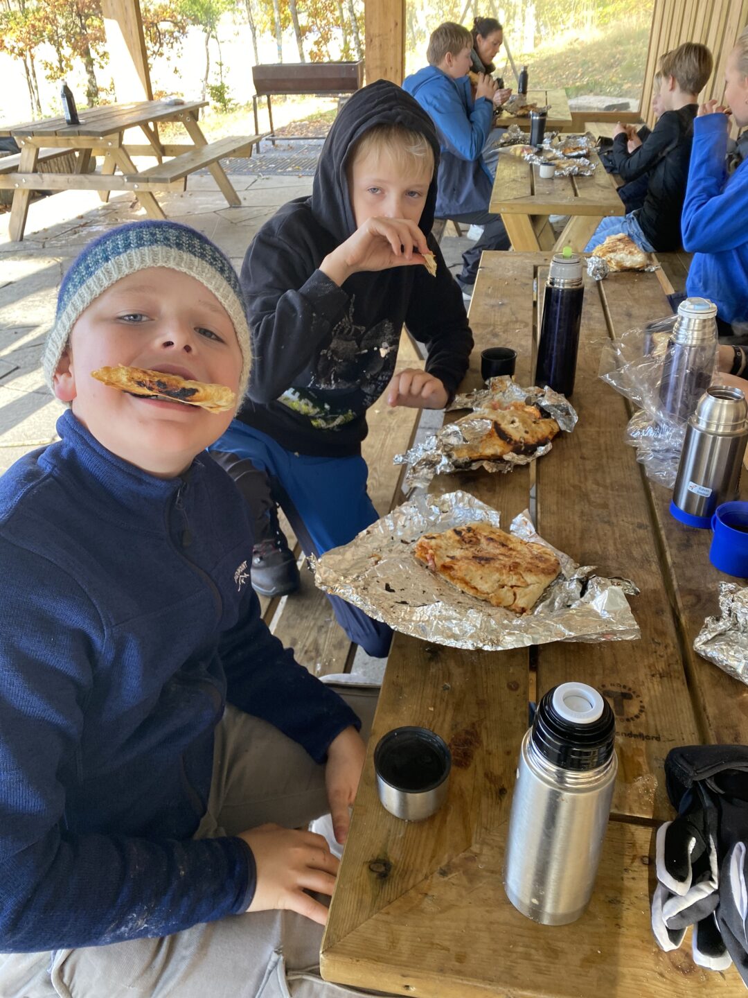 Bilder av elever som spiser pizza laget på bål.