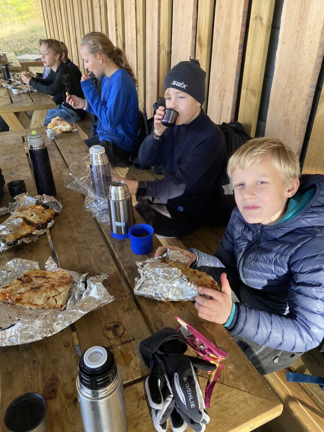 Bilde to av elever som spiser pizza laget på bål.