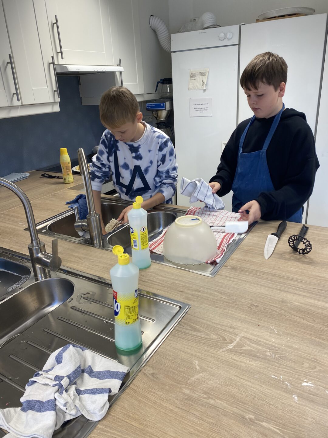Bilde av to gutter som vasker opp på skolekjøkkenet.