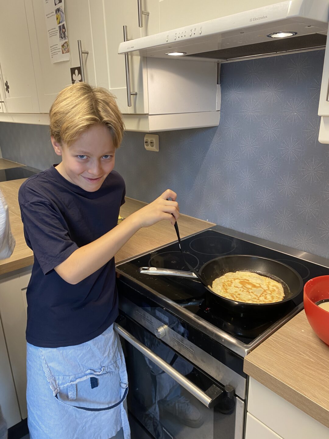 Bilde av gutt som steker pannekake på skolekjøkkenet.