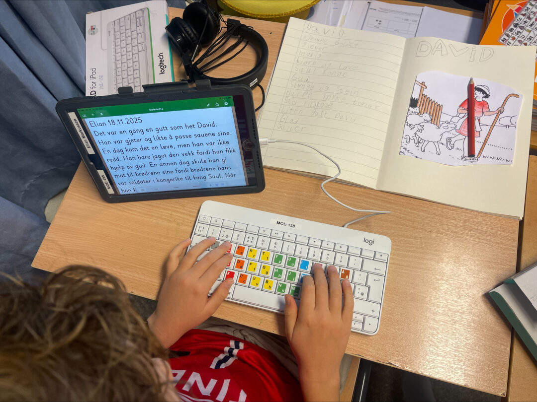 Bilde 2 av elev som skriver på tastatur til iPad, med tegning av David ved siden av.