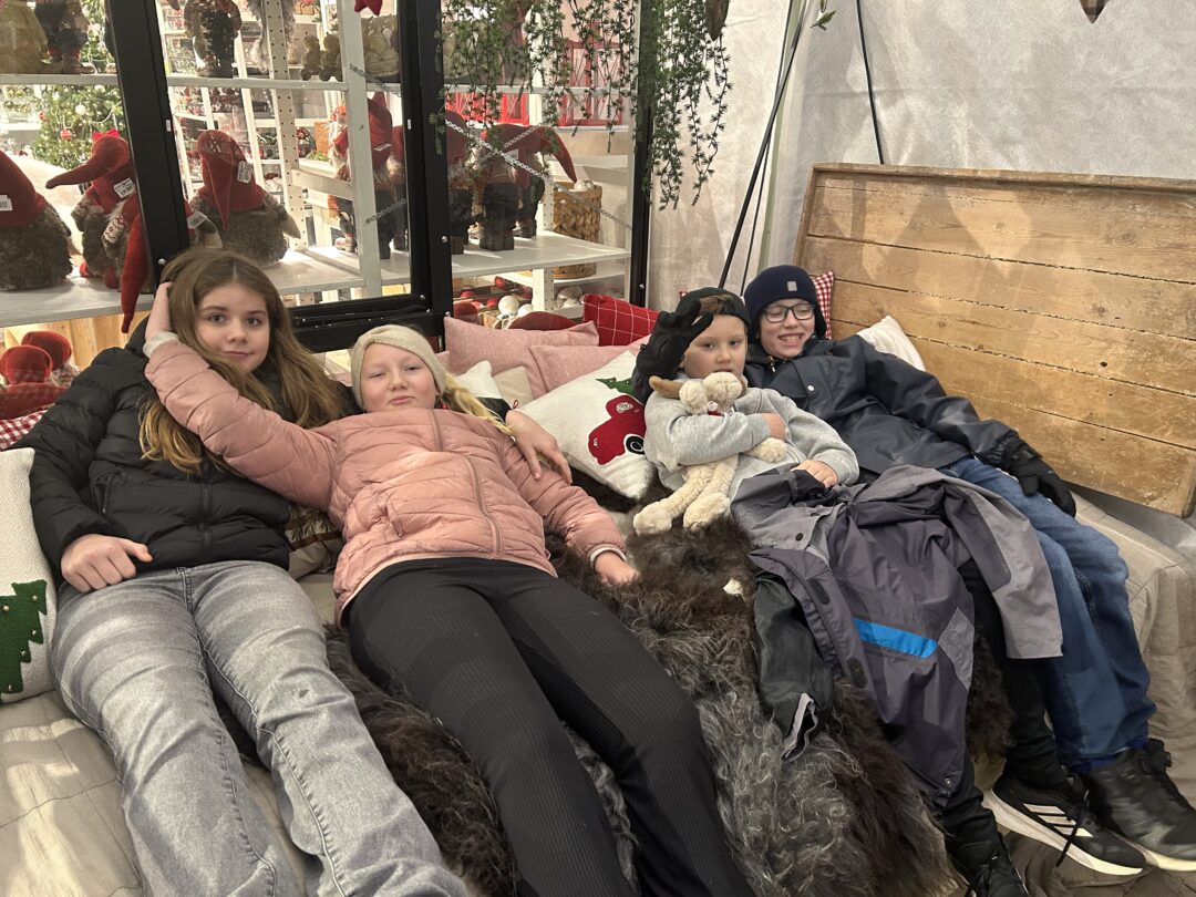 Bilde av fire elever som ligger mellom skinn og puter i juleutstilling på Gjennestad.