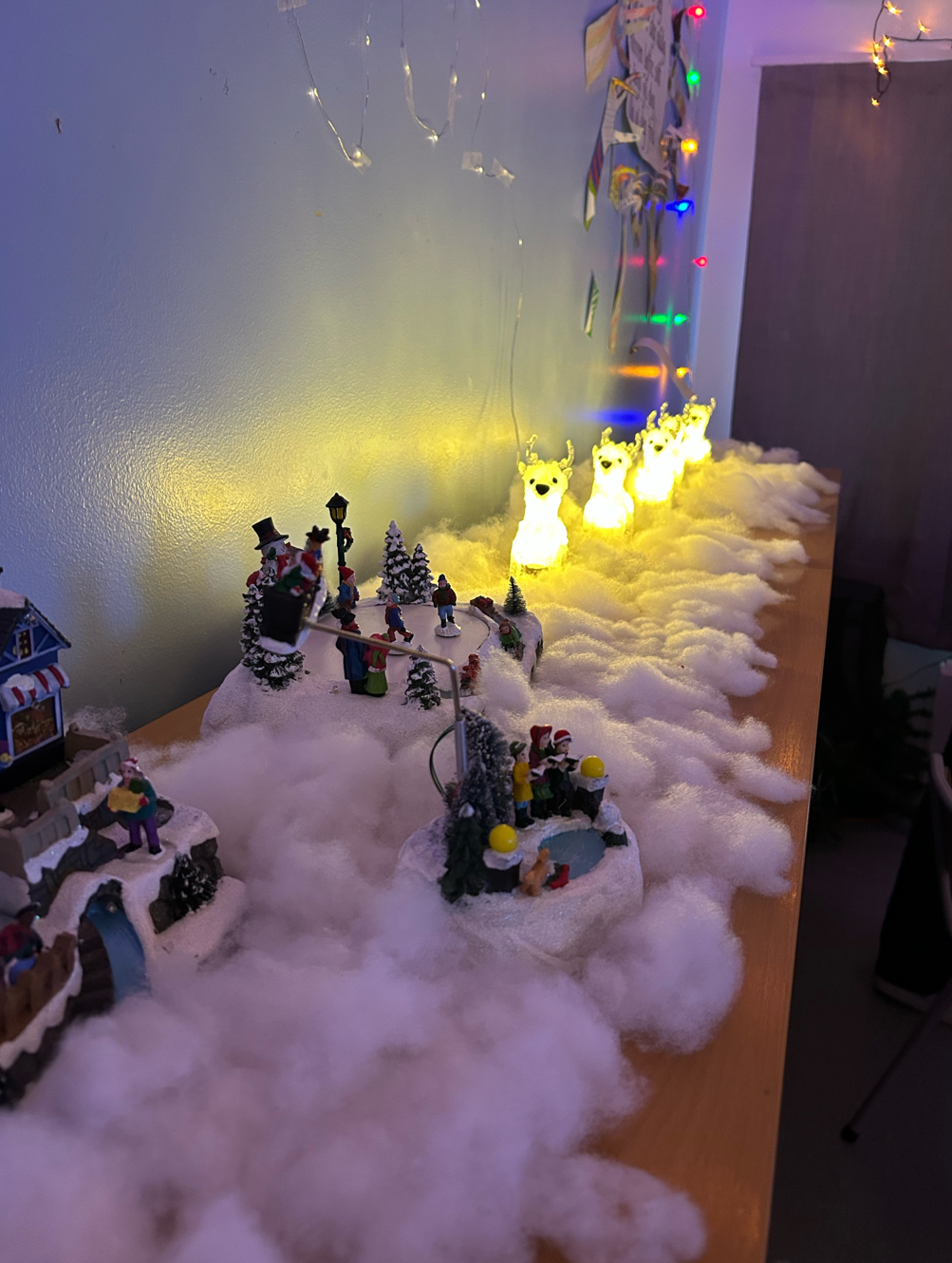 Bilde av julepynt i vatt på bord langs en vegg.