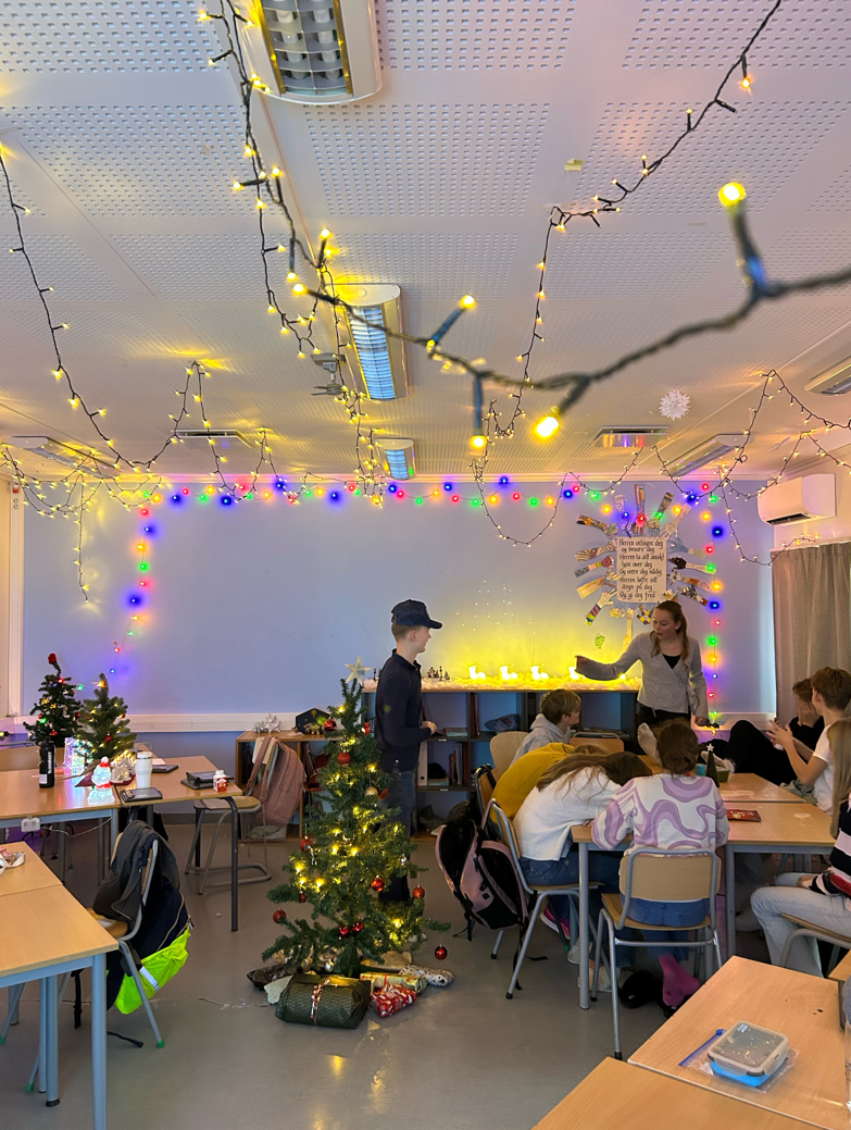 Bilde av julepyntet klasserom med juletre i midten.