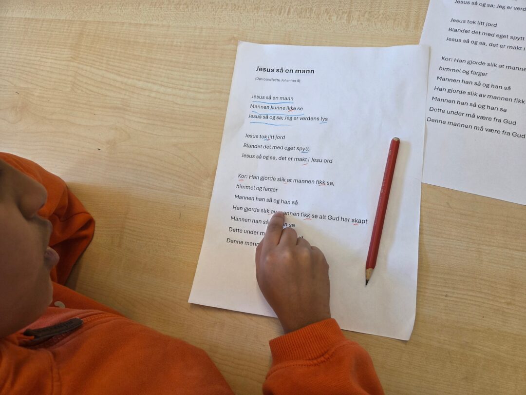 Bilde av elev som leser tekst på et ark.