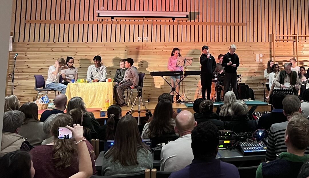 Bilde av skuespillere, sangere og musikere under påskespillet, og publikum.