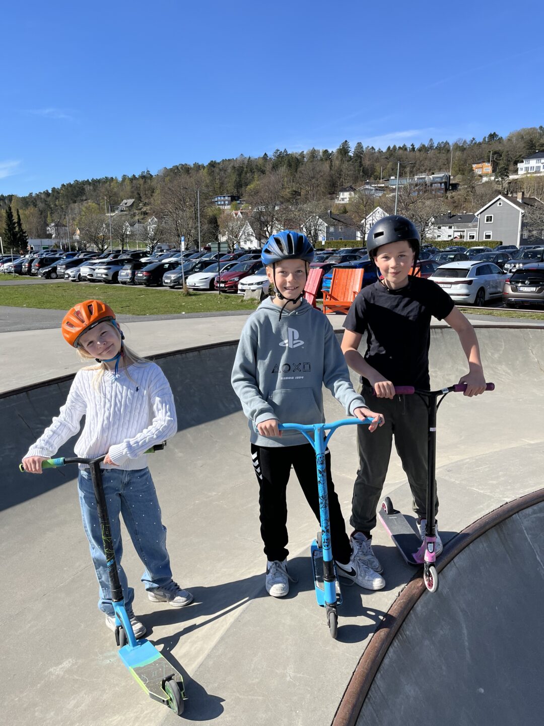 Bilde av to gutter og en jente på sparkesykkel i skateparken.