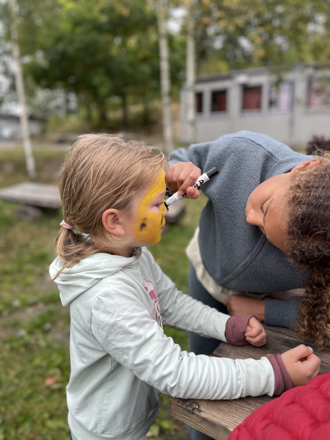 Bilde av stor jente som ansiktsmaler liten jente.
